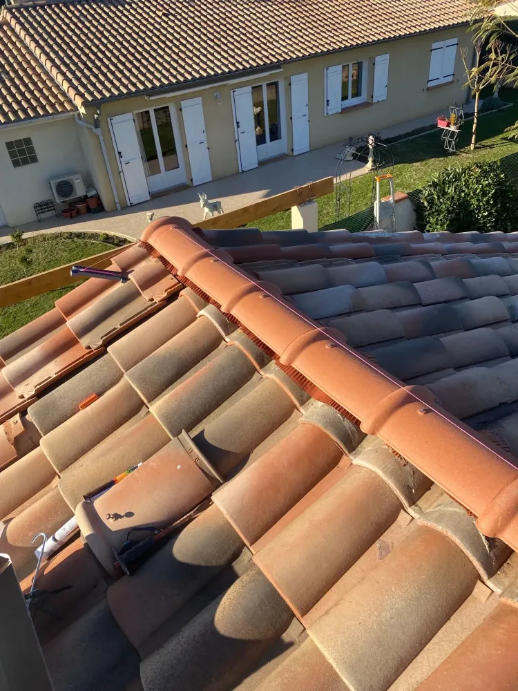 Pose de nouvelles tuiles faîtières sur un closoir ventilé, parfaitement alignées grâce à un cordeau rose tendu