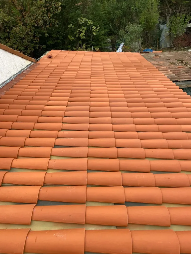 Large vue plongeante sur une toiture fraîchement rénovée avec des tuiles canal de couleur rouge terracotta bien alignées